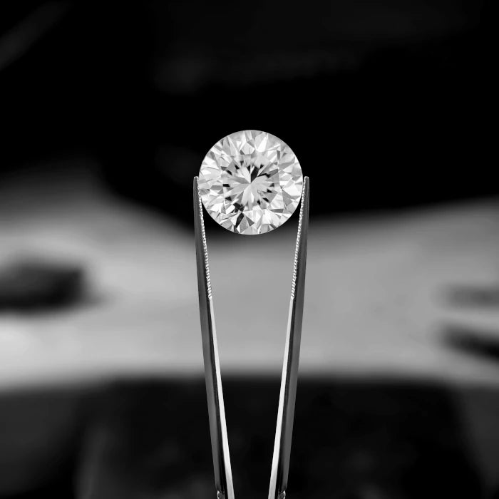 Diamant im Brillantschliff mit einer Pinzette geprüft